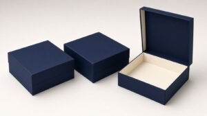 Three blank navy rigid gift boxes, two closed and one open with its lid raised to show the cream interior, in a magnetic gift box set